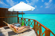 Young woman on chaise lounge under parasol