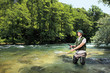 Fisherman fishing on a river with forest in the background