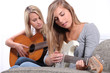 Two young women playing the guitar.