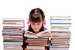 Little girl reading a book sitting among stacks of books