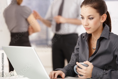 Photo: Young woman working on laptop in office Young woman working on laptop in office