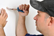 Handwerker zieht Dübel aus Wand