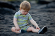 Portrait of a sad toddler sitting on black sand beach