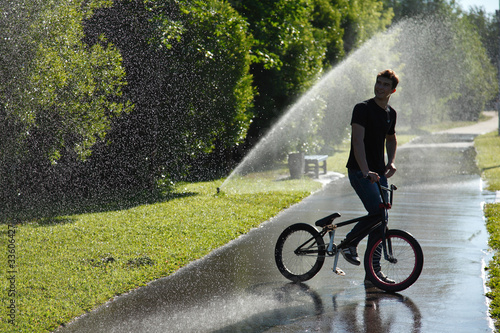 Photo: boy with bmx stay on fountain splashes background boy with bmx stay on fountain splashes background