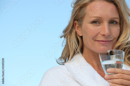 Photo: Attractive blonde haired woman drinking a glass of water Attractive blonde haired woman drinking a glass of water