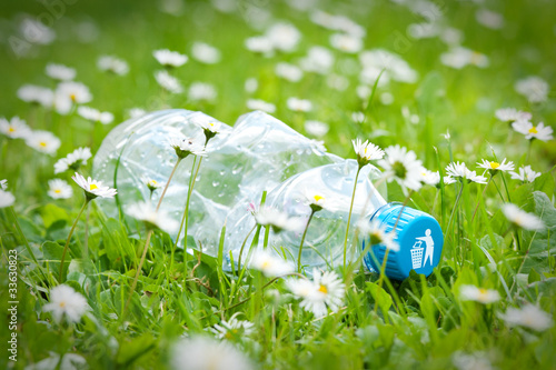Photo: Plastic bottle on grass with recycle logo Plastic bottle on grass with recycle logo