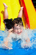 Young boy splashes into pool after going down water slide Young boy splashes into pool after going down water slide