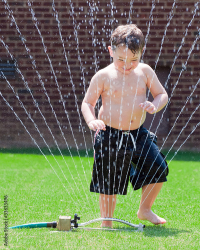 Photo: Young boy plays in water sprinkler Young boy plays in water sprinkler