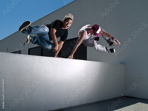 Photo: two male parkour free runners jumping over a wall two male parkour free runners jumping over a wall