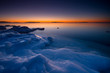 Sunrise on icy beach in early winter morning.