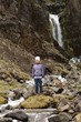 Foto: Frau steht vor einem natürlichen Wasserfall in Island Frau steht vor einem natürlichen Wasserfall in Island