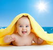 Adorable happy baby in colorful towel on sea beach