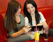Photo: Girls in cafe using modern tablet PC Girls in cafe using modern tablet PC