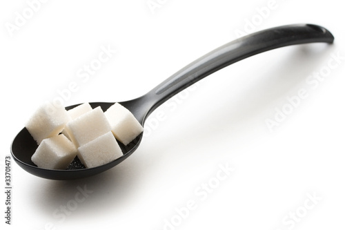 Photo: Sugar in a spoon isolated over white background Sugar in a spoon isolated over white background