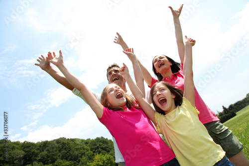Photo: Cheerful family lifting arms up in the air Cheerful family lifting arms up in the air