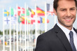 Foto: Smiling male executive in front of various flags Smiling male executive in front of various flags