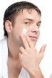 Man putting on cream lotion on face