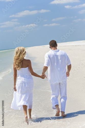 Photo: Happy Young Couple Running or Walking Holding Hands on Beach Happy Young Couple Running or Walking Holding Hands on Beach