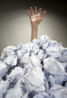 Hand reaches out from heap of papers