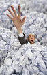 Businessman sinking in big heap of crumpled papers