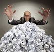 Serious businessman reaches out from crumpled papers