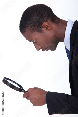 Photo: black man looking through a magnifying glass black man looking through a magnifying glass