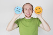 young man in green shirt holding emotion smile symbols