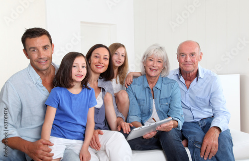 Photo: 3-generation family sitting in couch with electronic tablet 3-generation family sitting in couch with electronic tablet