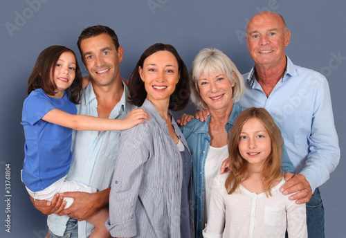 Photo: Portrait of happy family standing ion grey background Portrait of happy family standing ion grey background