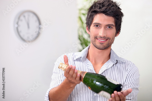Photo: Man offering a bottle of champagne at five minutes to midnight Man offering a bottle of champagne at five minutes to midnight