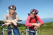 Photo: Senior couple riding mountain bikes in natural landscape Senior couple riding mountain bikes in natural landscape