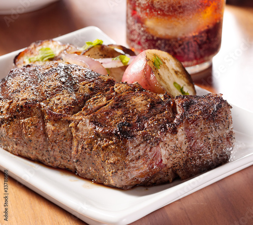 Photo: grilled steak with potatoes and cola in background. grilled steak with potatoes and cola in background.