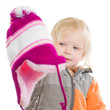 Adorable toddler girl dressing winter jacket and hat. holding ha