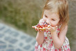 Little girl eating a strawberry tart outdoors