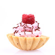 Tartlet with whipped cream, a raspberry and sprinkles on white Tartlet with whipped cream, a raspberry and sprinkles on white