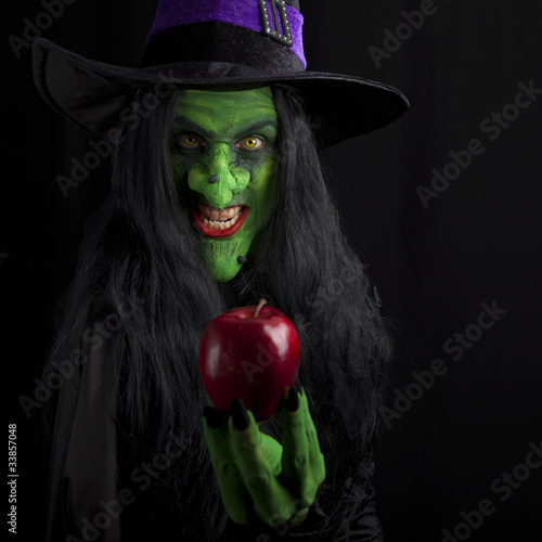 Photo: Witch and her red poison apple, dark background. Witch and her red poison apple, dark background.