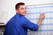 an employee dressed in blue jumpsuite is writing on a calendar