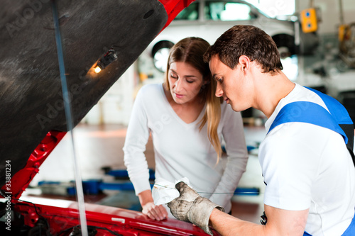 Photo: Woman talking to car mechanic in repair shop Woman talking to car mechanic in repair shop