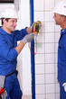 Two young plumbers larking about with a voltmeter