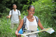 Woman map reading while hiking through long grass