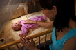 young mother sitting by the crib with 7 week old baby