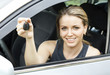 Beautiful young happy woman in car showing the keys