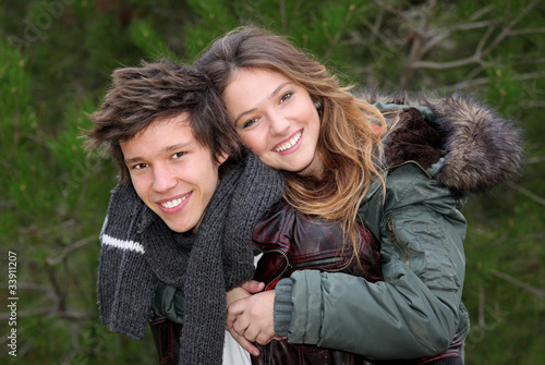 Photo: happy smiling winter teen couple in piggy back happy smiling winter teen couple in piggy back