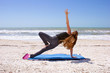 Photo: woman doing yoga exercise on beach in Vasisthasana or side plank woman doing yoga exercise on beach in Vasisthasana or side plank