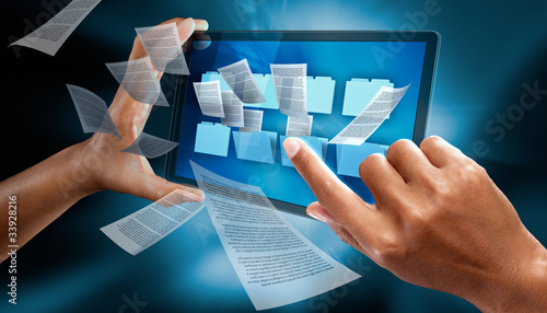Photo: A woman use a digital tabler, PDA, to check folders A woman use a digital tabler, PDA, to check folders