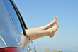 women with bare feet out the window of the car road on vacation