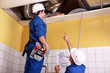 two technicians checking the air conditioning in the ceiling