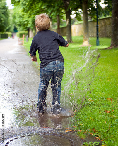 Foto: boy is jumping in a puddle boy is jumping in a puddle