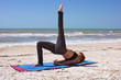 Photo: woman doing yoga exercise one leg bridge pose on beach woman doing yoga exercise one leg bridge pose on beach