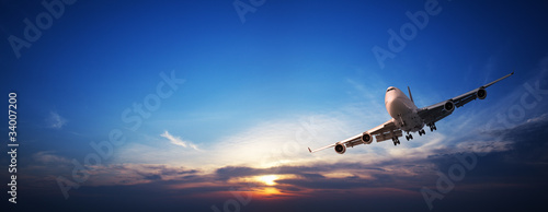 Photo: Jet cruising in a sunset sky. Panoramic image. Jet cruising in a sunset sky. Panoramic image.
